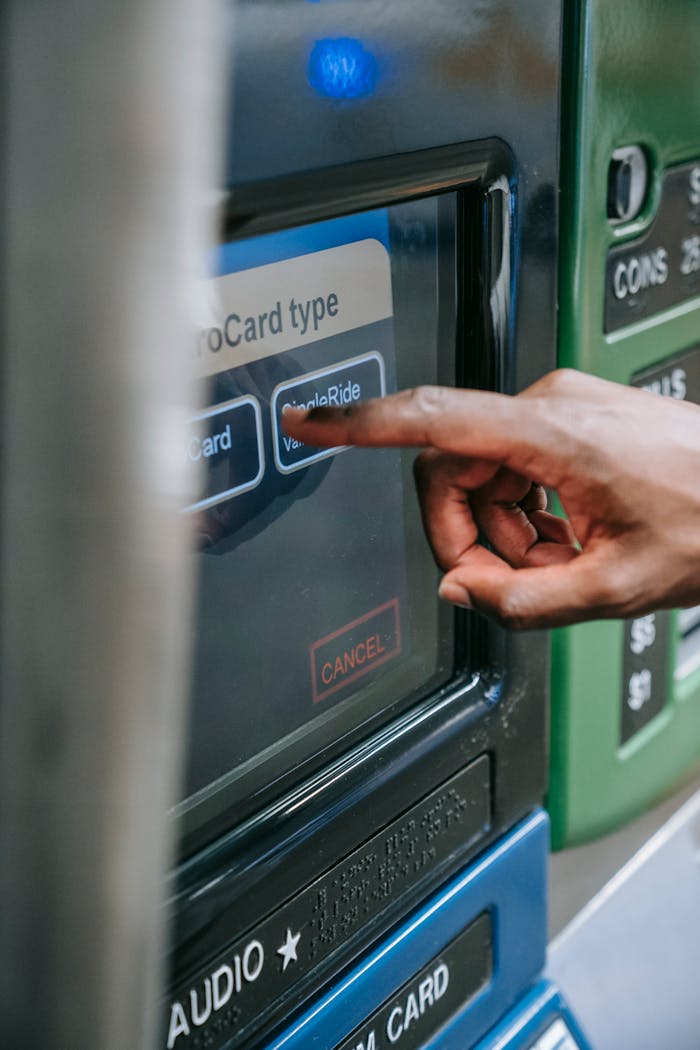 Close-up of a hand using a touchscreen on an ATM or ticket machine to select a card type.